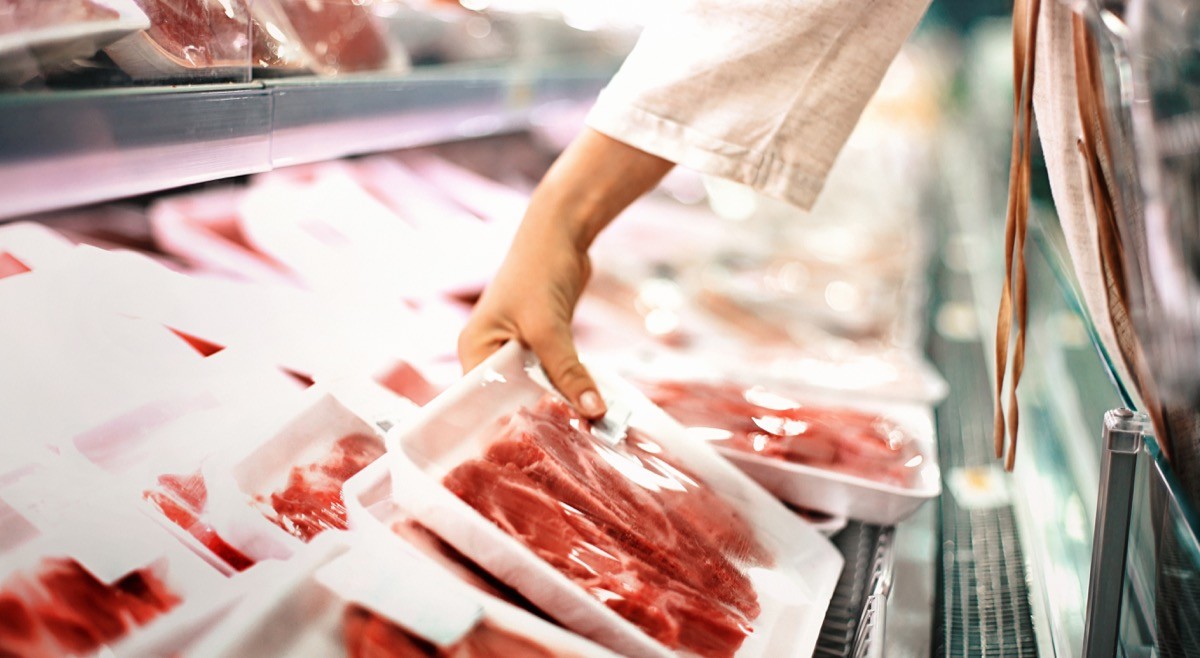 Closeup side view of a woman selecting packaged meat