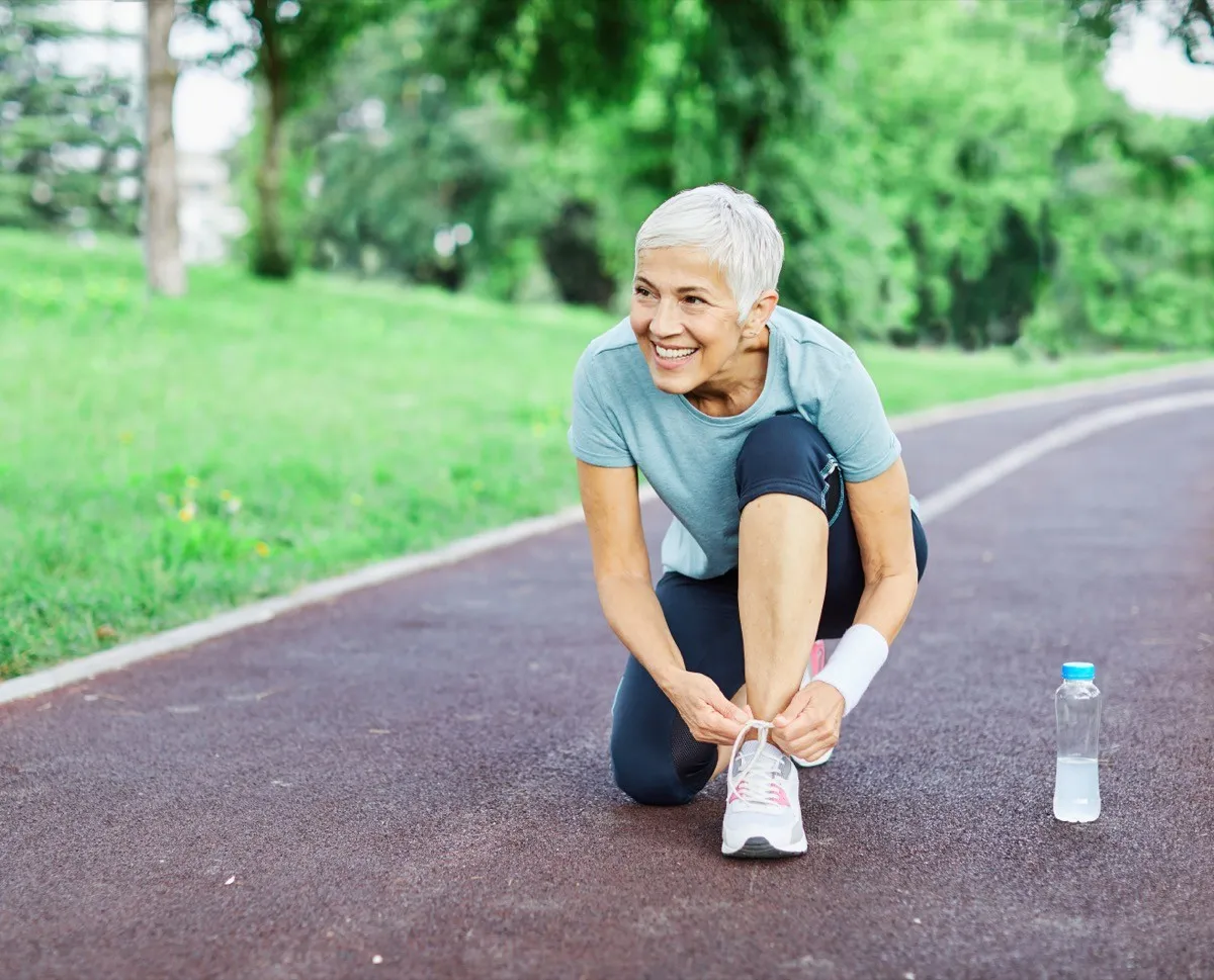 A happy active senior woman lacing her shoes