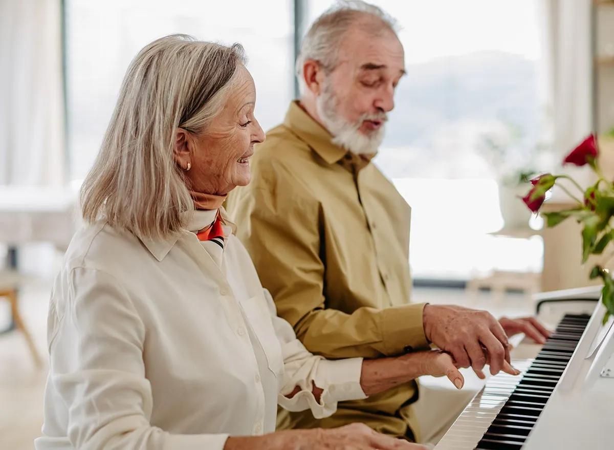 A senior couple playing piano together