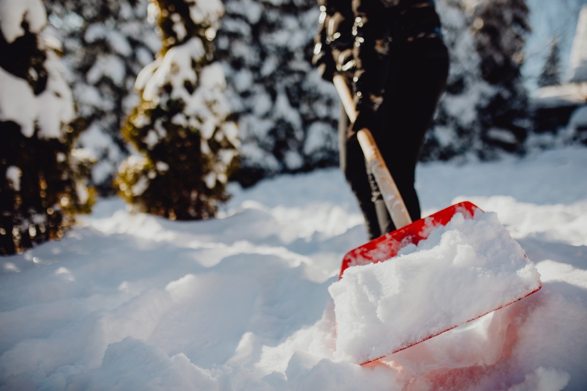 A person shoveling snow during heavy winter blizzard