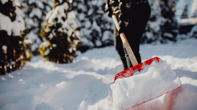 A person shoveling snow during heavy winter blizzard