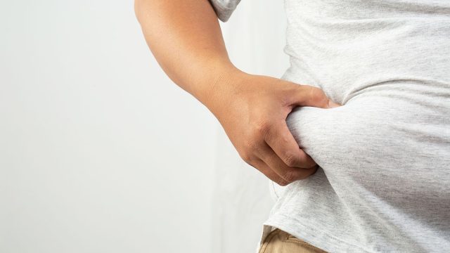 closeup of a man grabbing his belly fat
