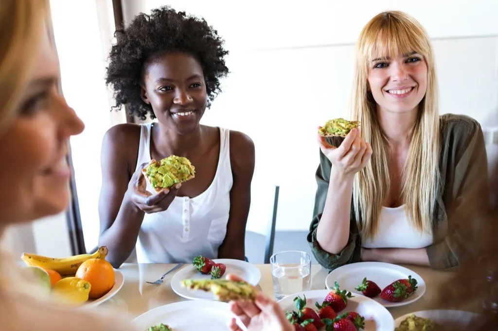 Friends eating avocado toast with fresh berries