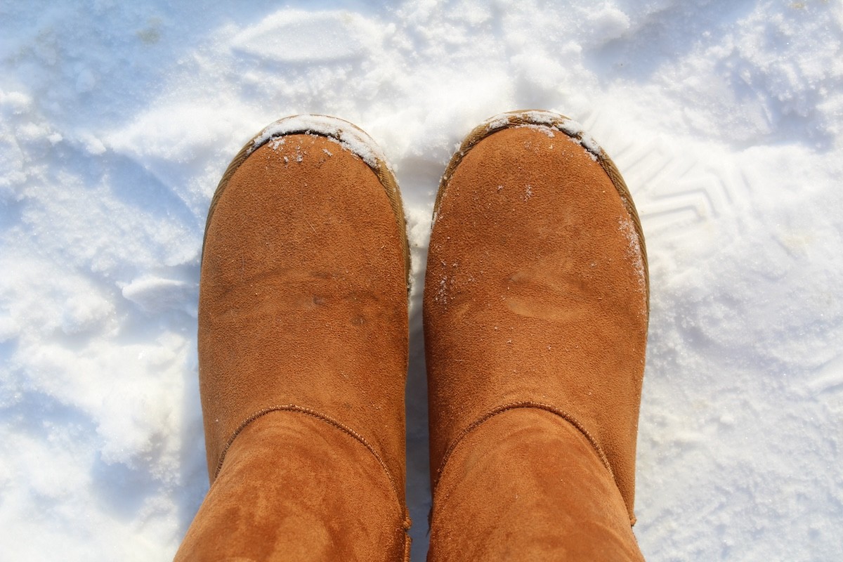 closeup of someone wearing Ugg boots in the snow