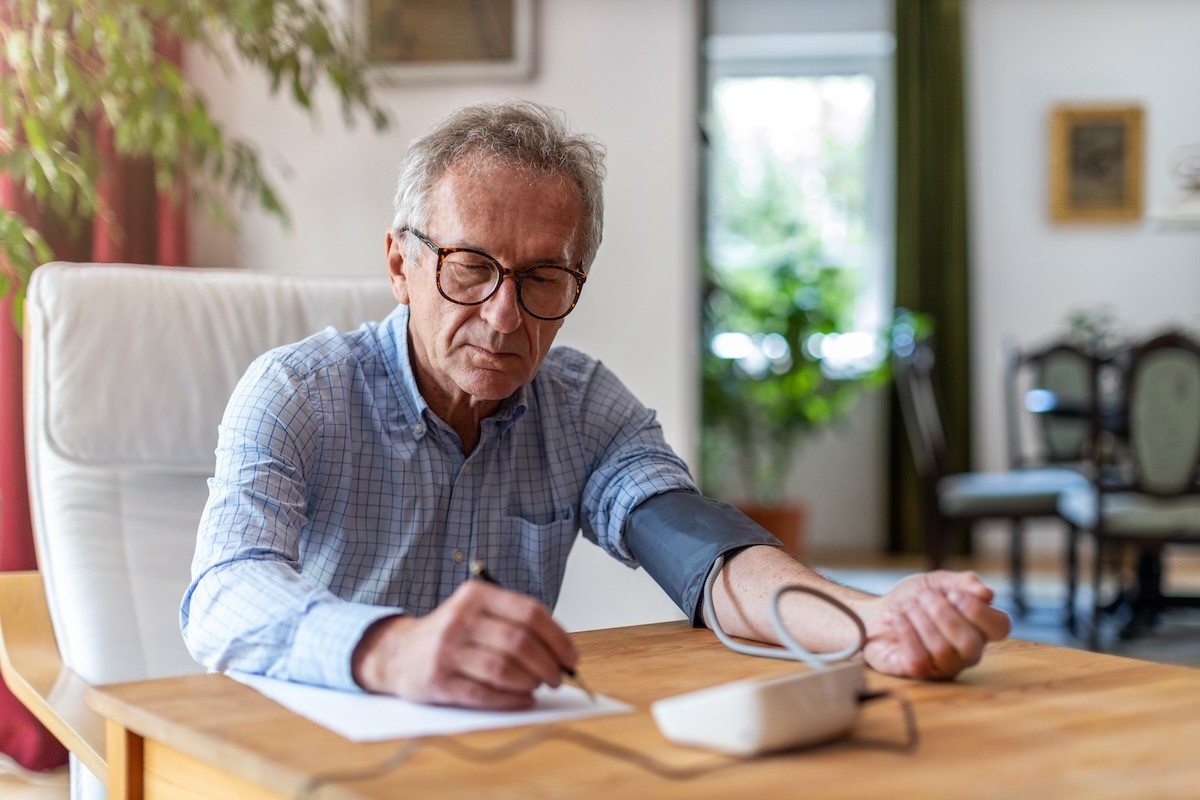 man recording his at-home blood pressure reading