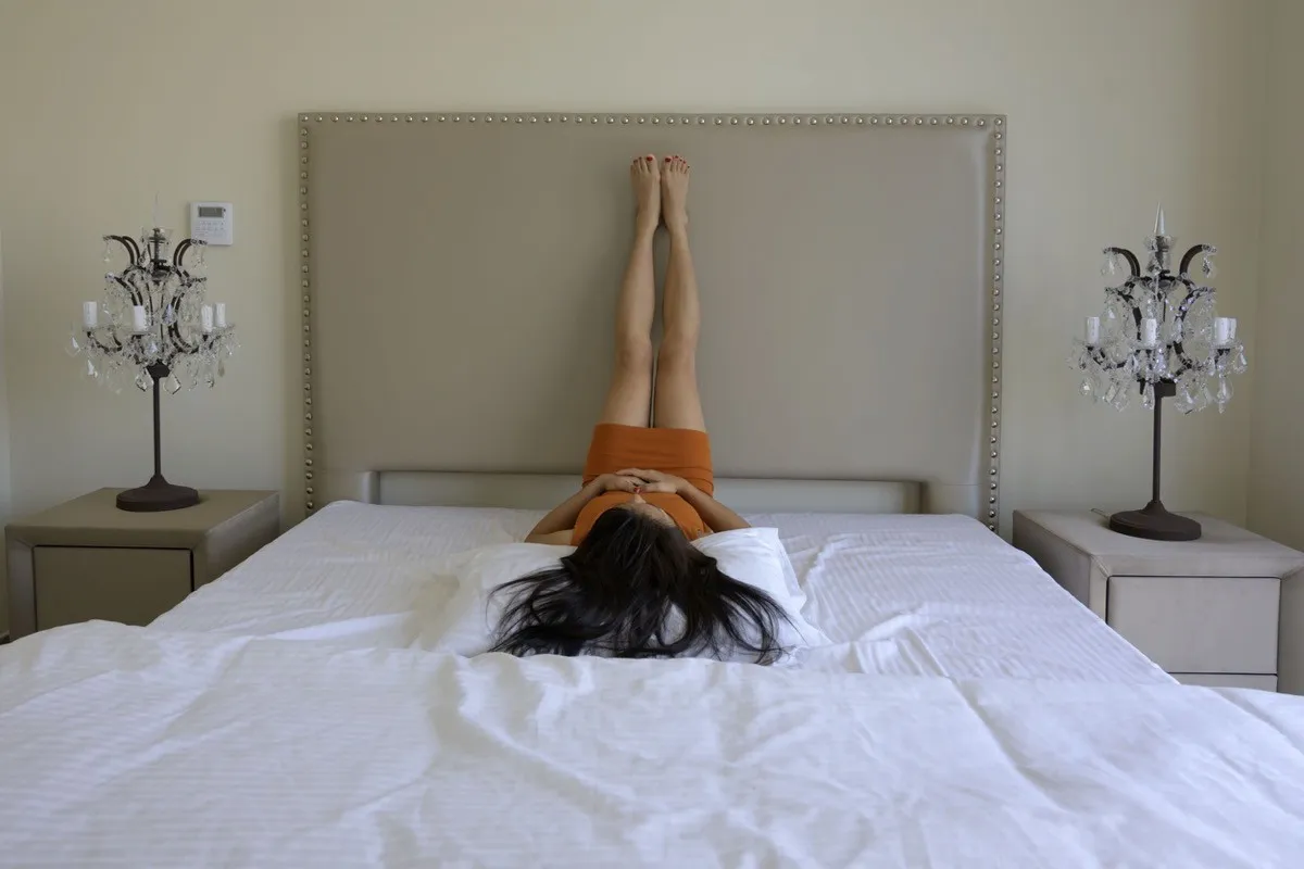 Woman feet up on head bed relaxing lying white pillow in bedroom background