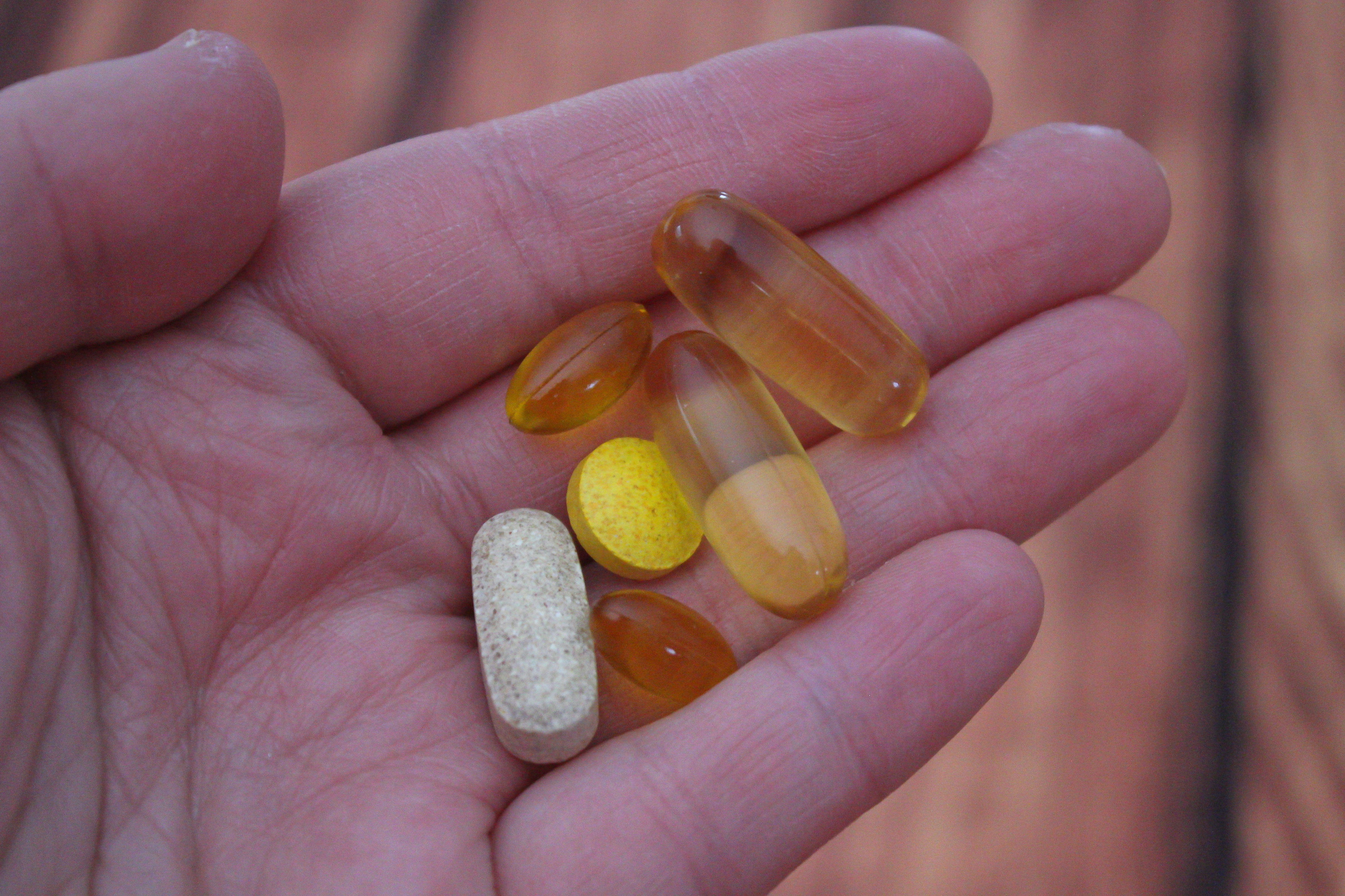 a person holds medications that they may take with vitamins