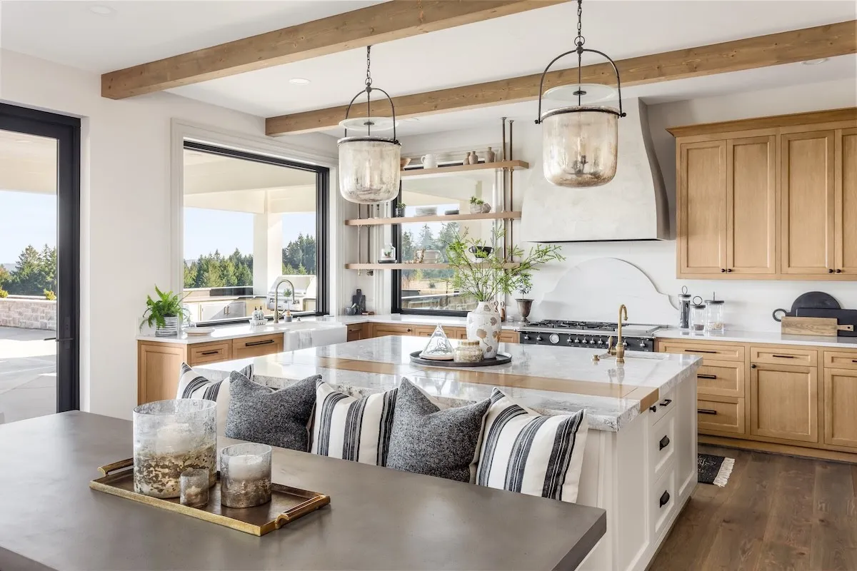 coastal-style kitchen with whites, navy blues, and woods and a large table built into the kitchen island