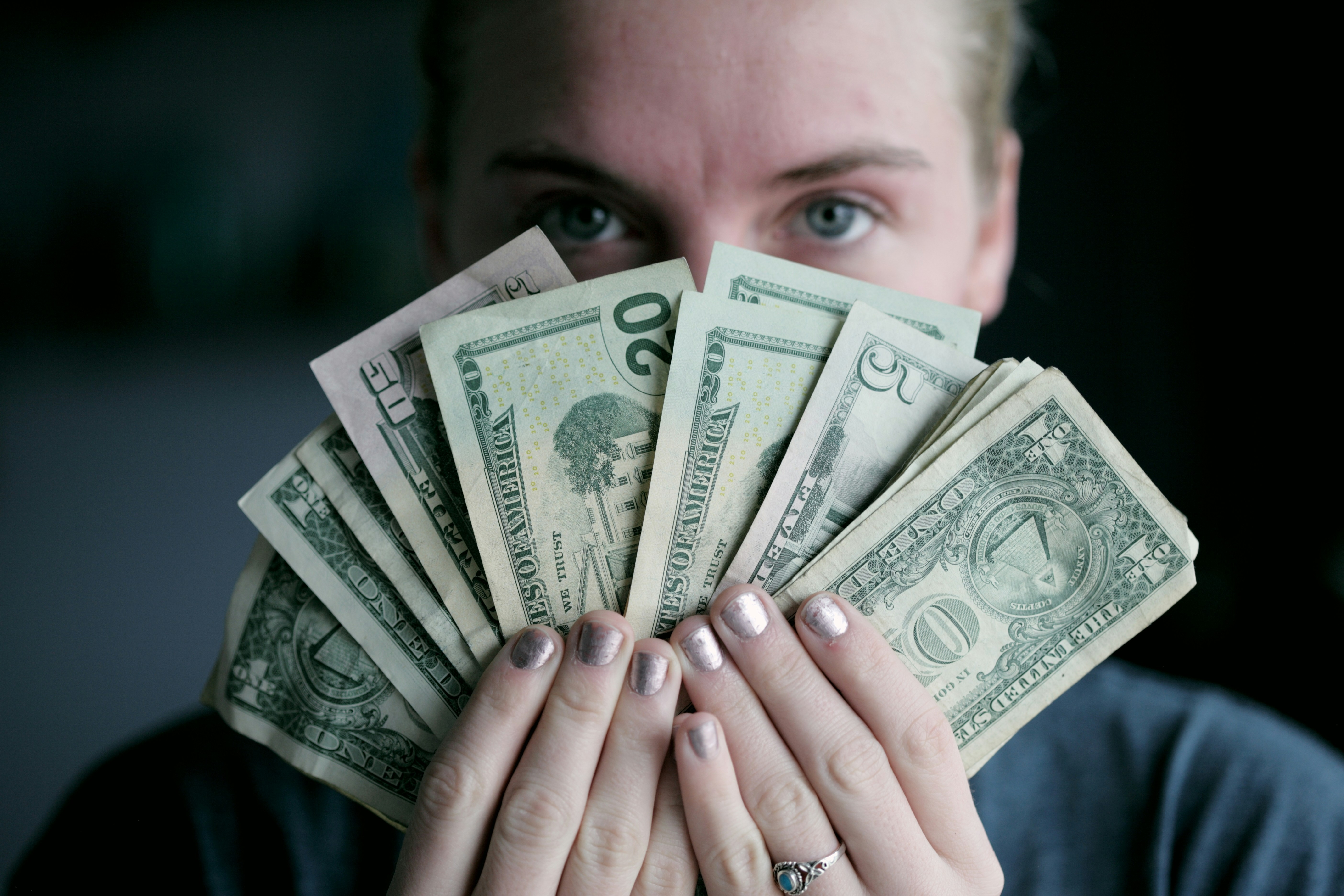a woman holds out a wad of united states dollars