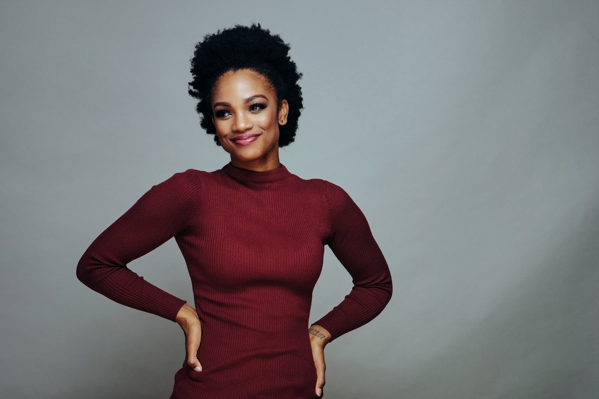 woman wearing a long-sleeved burgundy dress against a gray background