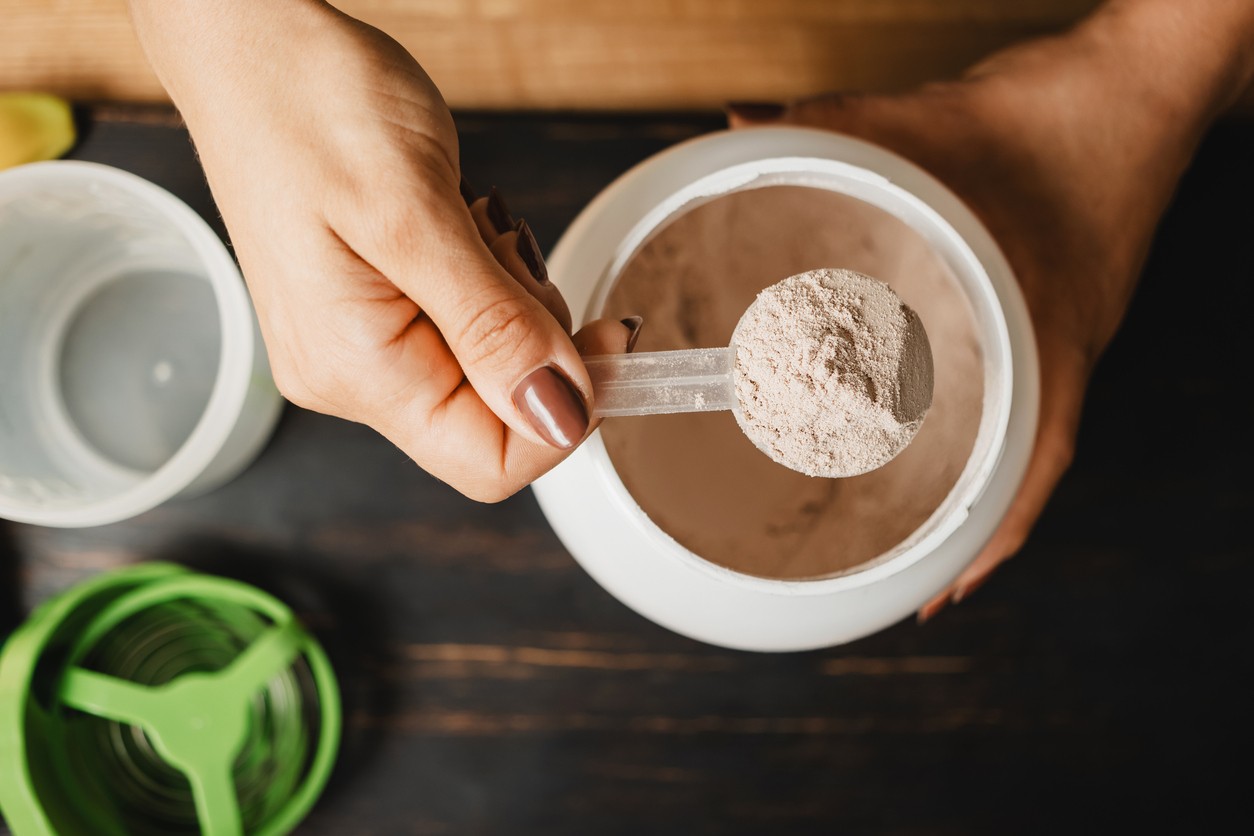 An overhead shot of someone scooping creatine out of a container