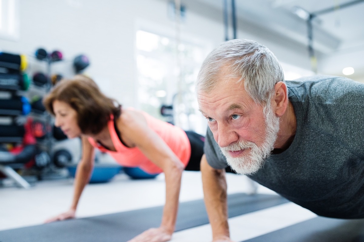mature couple doing push ups at the gym