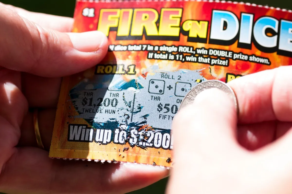 close up of person using a penny on a scratch-off ticket