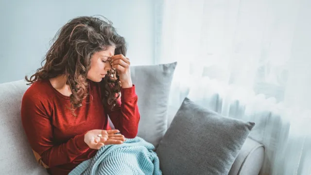 Close up image woman holding round pill and glass of still water taking painkiller to relieve painful feelings migraine headache, antidepressant or antibiotic medication, emergency treatment concept