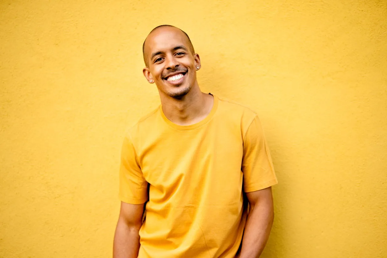 smiling young man in yellow t-shirt on yellow wall