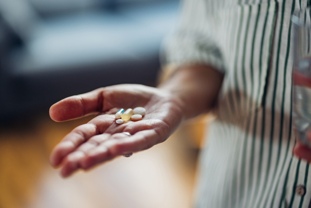 A close up of a person's hand holding supplements or medication
