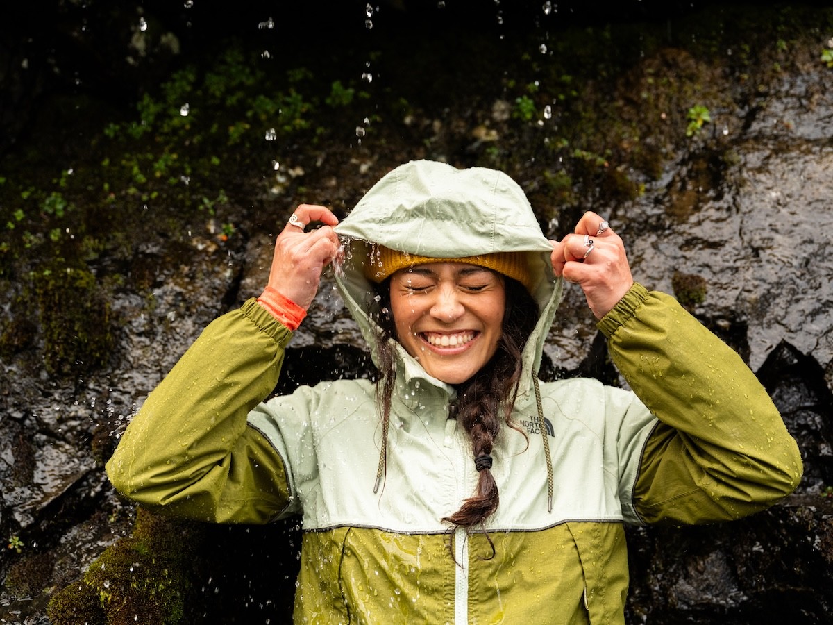 smiling woman in a rain jacket getting wet while on a hike