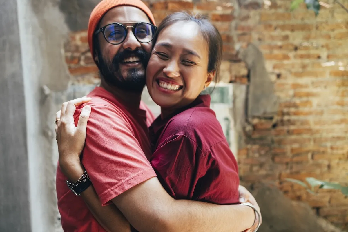 couple wearing red hugging in front of a brick wall