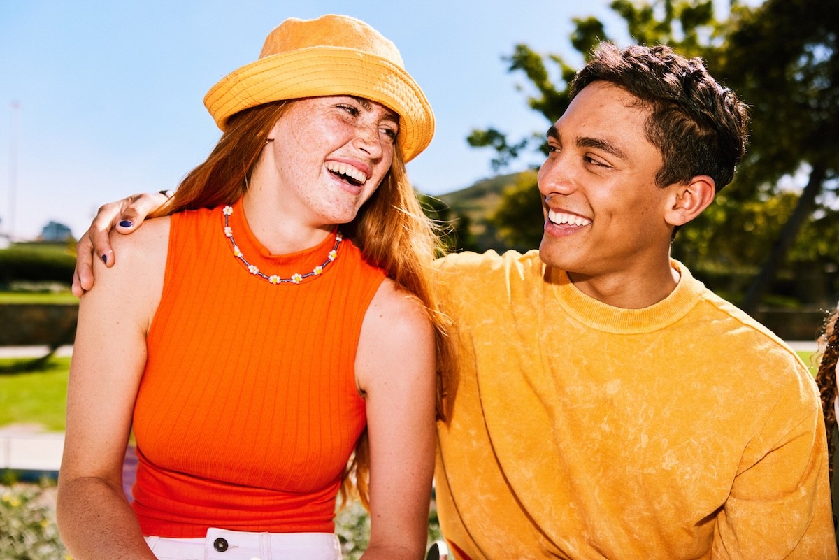 smiling young couple sitting outside dressed in orange