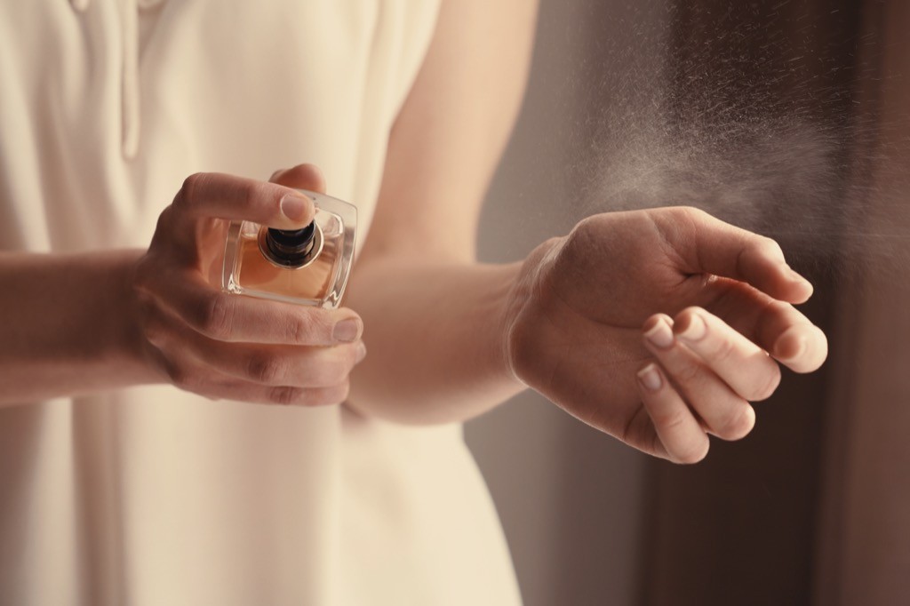 woman spraying perfume on wrist