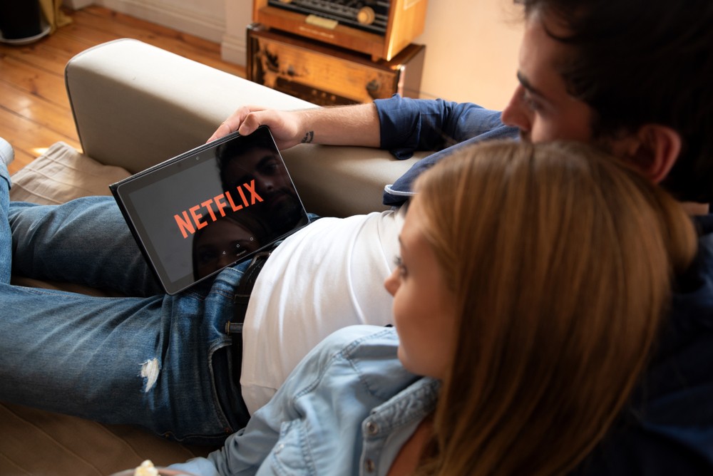 A couple watching Netflix on their tablet while sitting on a couch
