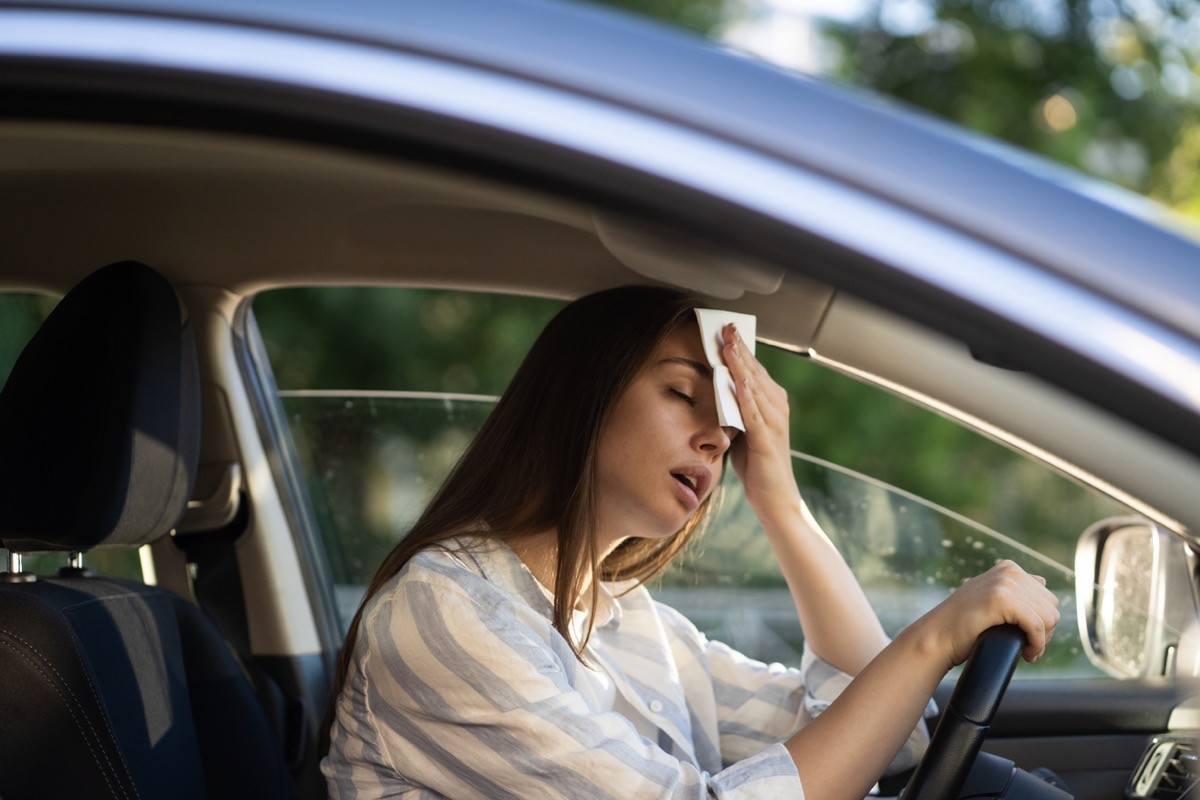 female driver overheated while driving and wiping her head with a napkin