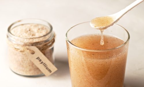 jar of psyllium husk powder next to a glass of psyllium mixed with water