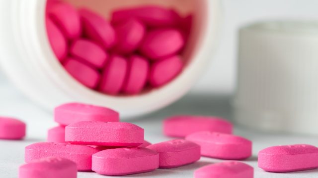 closeup of pink Benadryl pills spilling out of the bottle