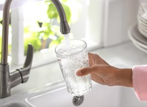 closeup of a woman filling a glass with tap water