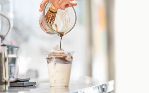 closeup of a barista making an iced hojicha latte