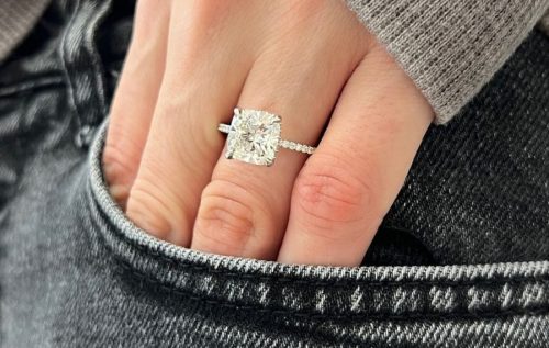 woman with her hand part way in her jeans pocket wearing a cushion-cut diamond engagement ring