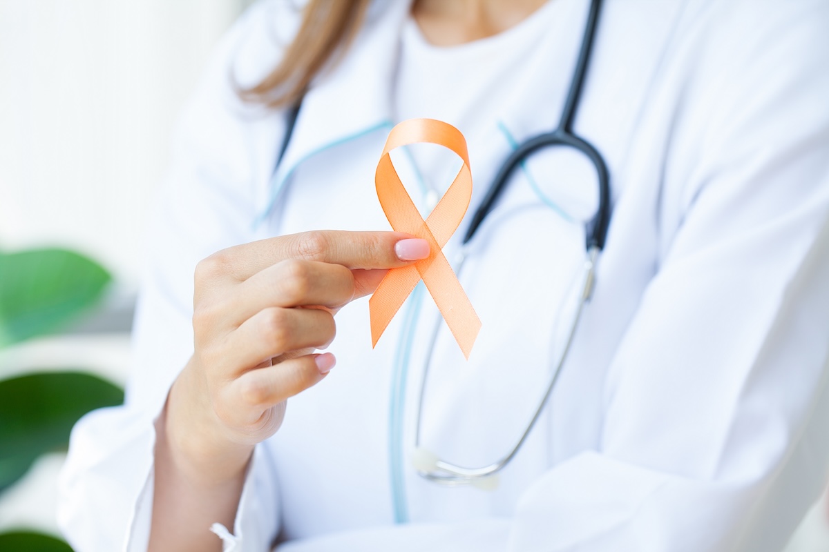 Close up of a doctor holding and showing orange awareness ribbon for Multiple Sclerosis