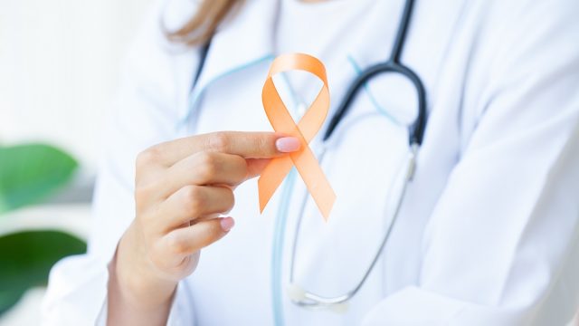 Close up of a doctor holding and showing orange awareness ribbon for Multiple Sclerosis