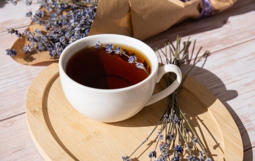 mug of lavender tea on a wooden plate surrounded by dried lavender