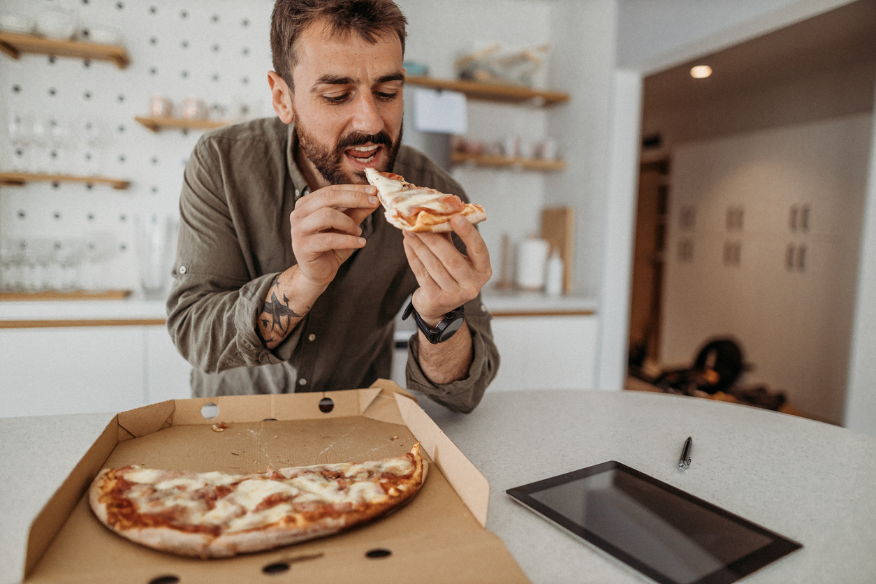 A man eating pizza in his kitchen