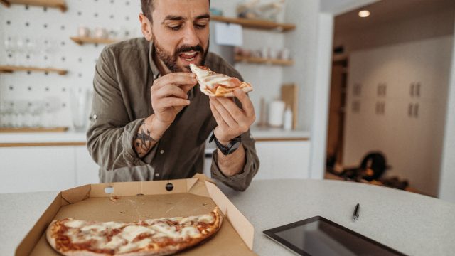 A man eating pizza in his kitchen