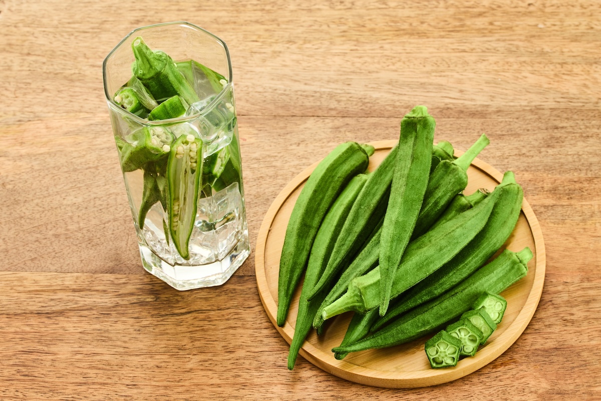 okra on a plate and a glass of okra water on a wooden background