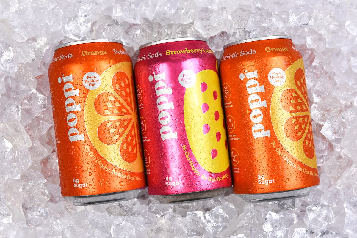 Three cans of Poppi Prebiotic Soda on a bed of ice.