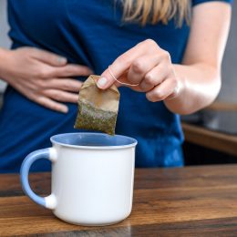 closeup of a woman with a stomach ache making a cup of tea