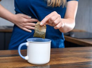 closeup of a woman with a stomach ache making a cup of tea