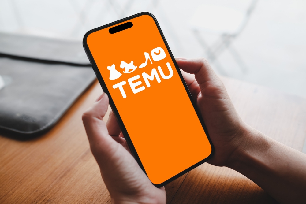 The Temu logo on a smartphone in someone's hand