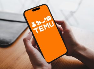 The Temu logo on a smartphone in someone's hand