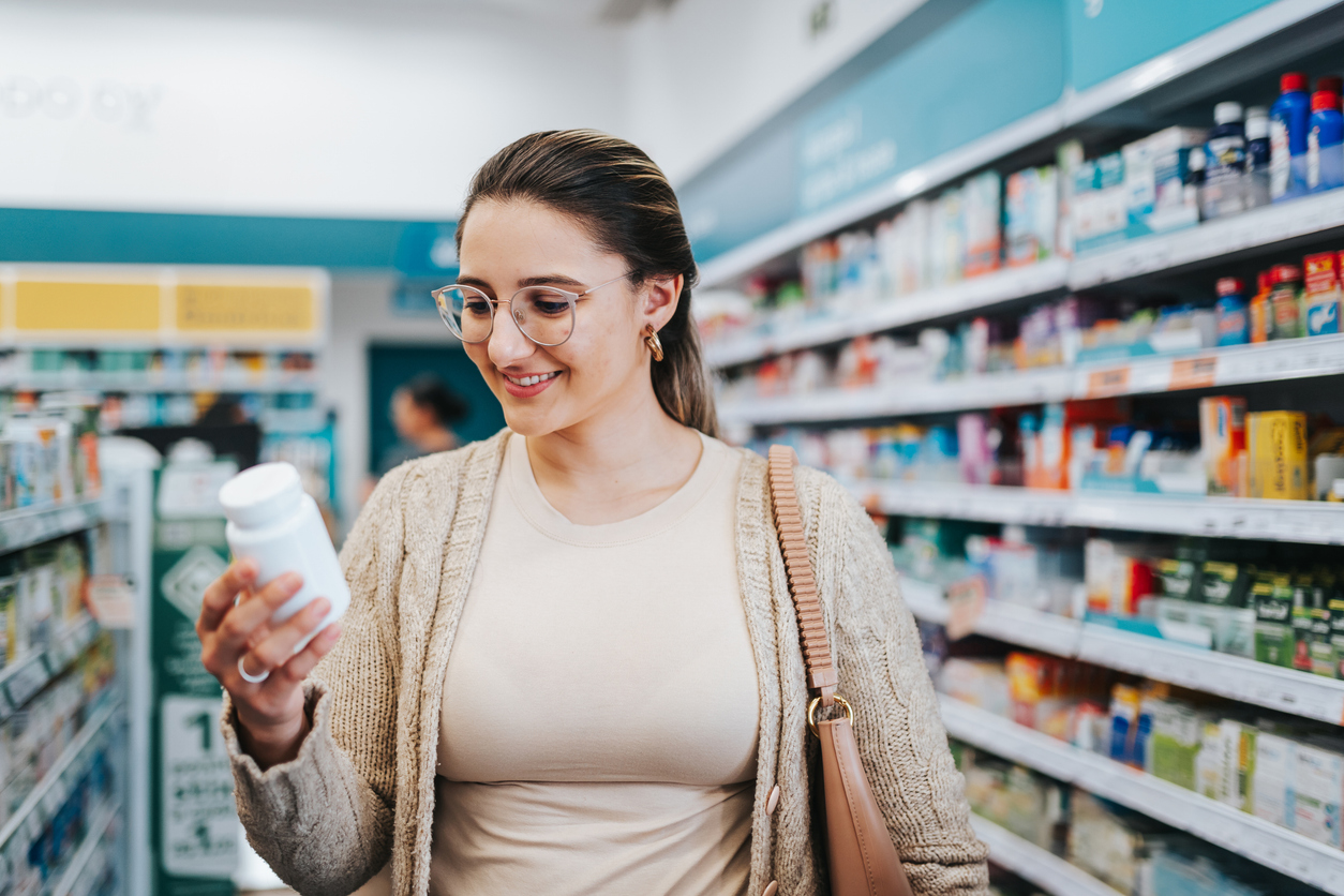 A woman looking at a bottle of supplements in the store