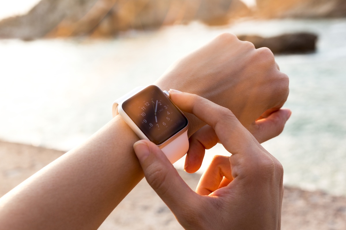 closeup of a female hand adjusting a pink apple watch outside