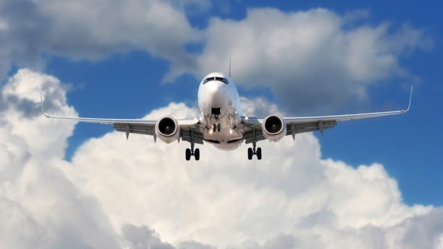 A jumbo jet flying in the sky with clouds in the background