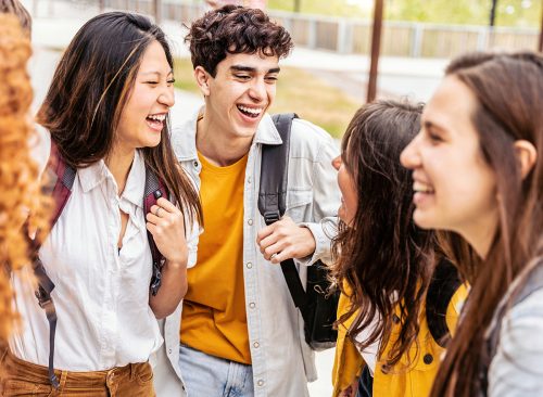 students talking and laughing together - Happy teenagers having fun going to school - Friendship concept with guys and girls hanging out on summer day