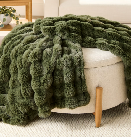 green throw blanket on an ottoman 