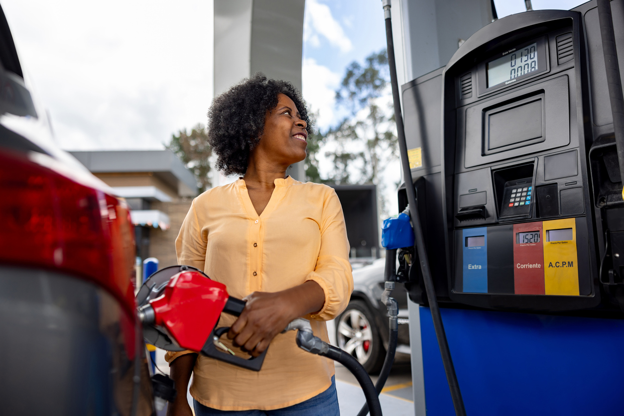 A woman filling up her car with gas at a station