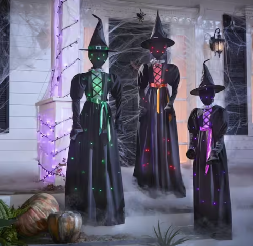three light-up witches in front of a house