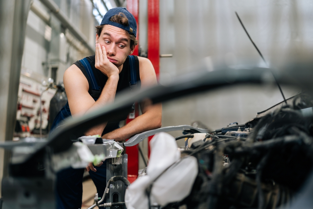 A frustrated mechanic looking at a car engine